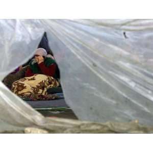  An Elderly Kosovar Woman Sits Behind a Plastic Wind Guard 